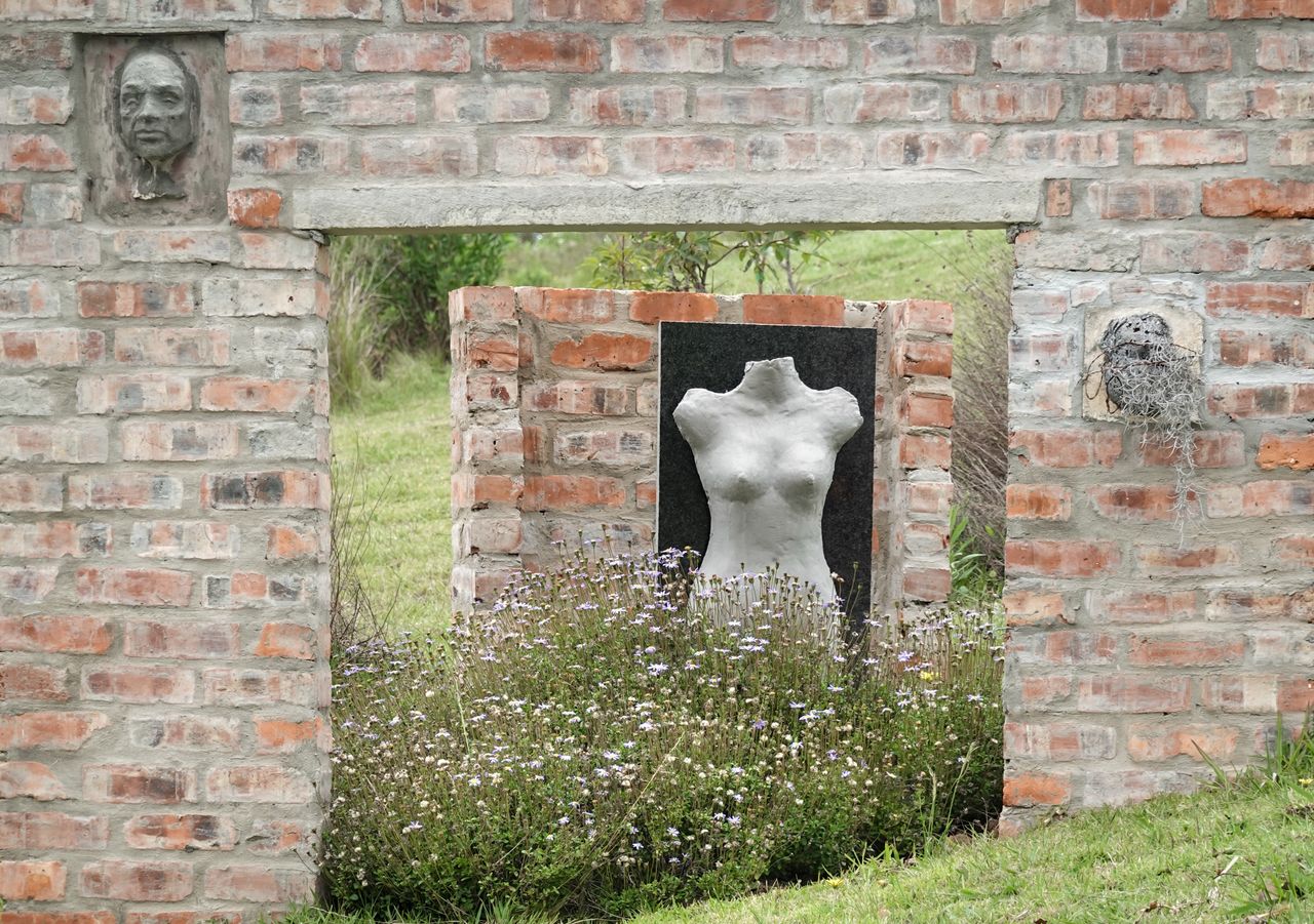 Crafting Captivating Headlines: Your awesome post title goes here Brick wall with sculptures in an outdoor garden setting, surrounded by flowers.