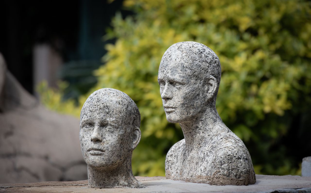 Mastering the First Impression: Your intriguing post title goes here Two lifelike stone sculptures of faces against a leafy backdrop, showcasing artistic craftsmanship.