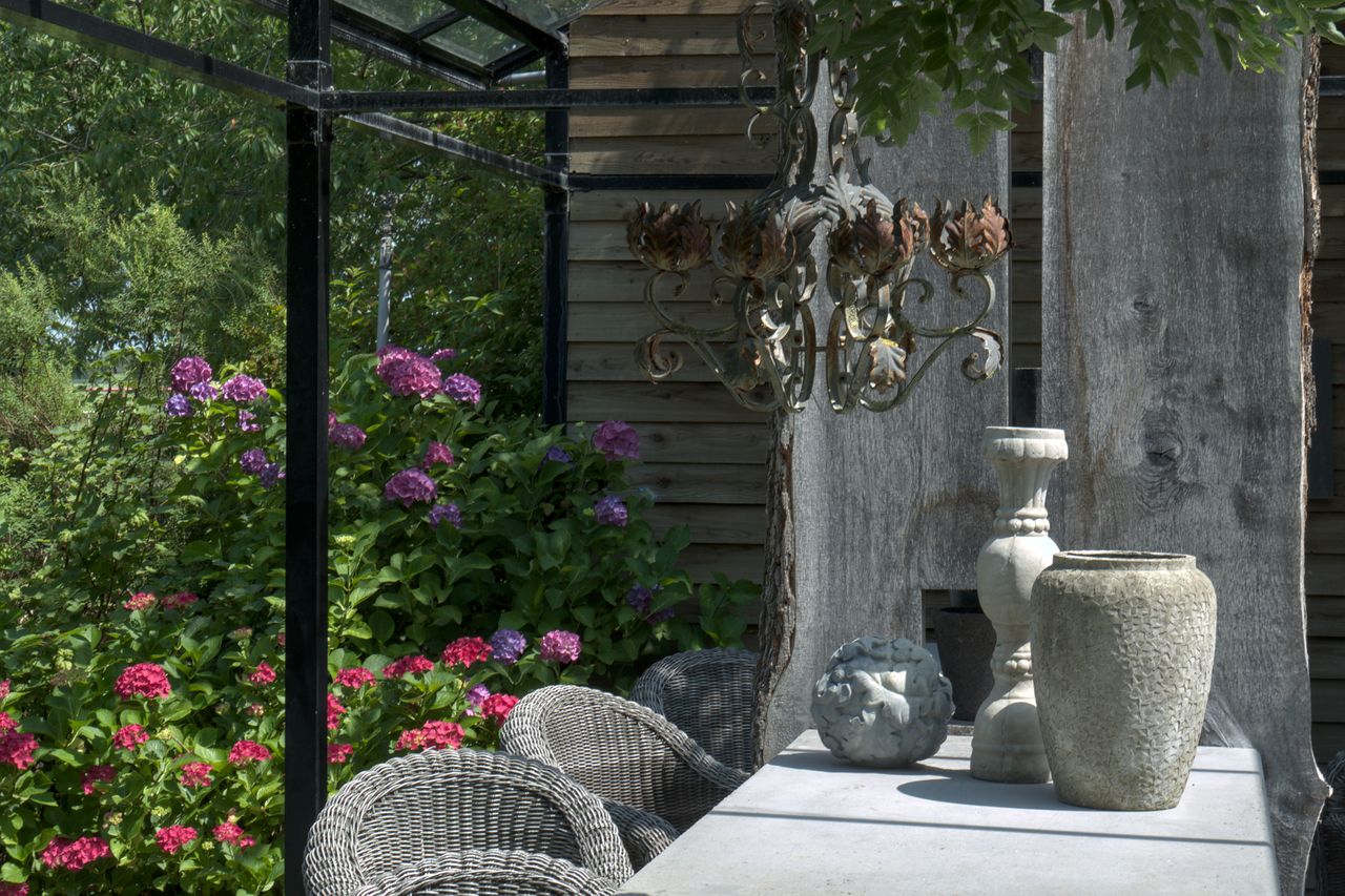 The Art of Drawing Readers In: Your attractive post title goes here A rustic outdoor garden table adorned with clay pottery and a chandelier amidst vibrant hydrangeas.